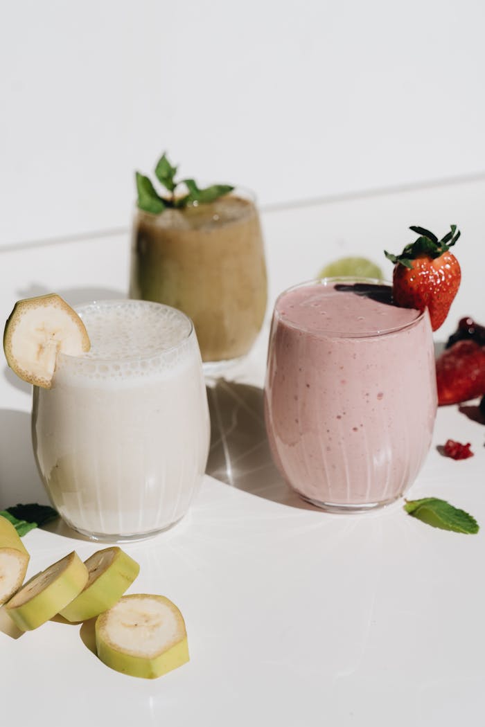 Three refreshing fruit smoothies, enjoying natural light with fruit garnishes.