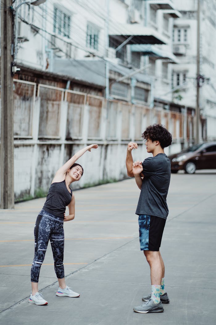 Two people stretching outside in an urban setting, focusing on fitness and health.